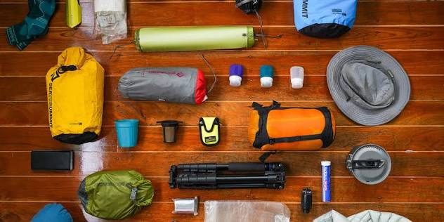 Dry bags, sleeping pad and compressed sleeping bag arranged on a wooden deck