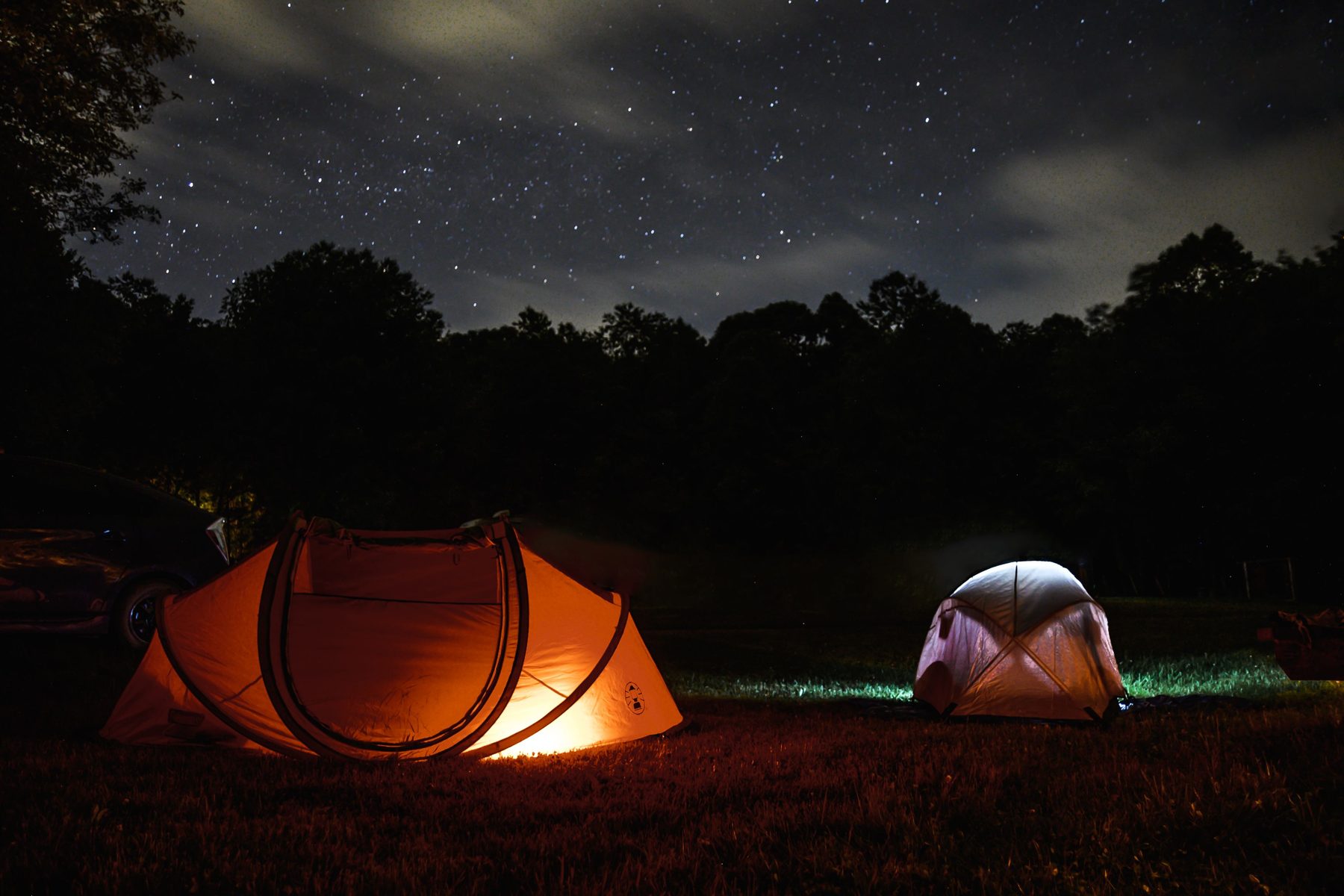 Pop-up tent and dome tent glowing under a starry night sky